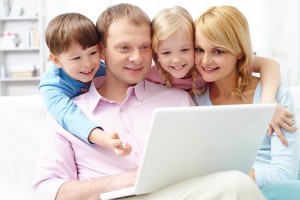 A young family of four using laptop at home