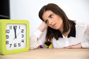 Businesswoman sitting at the table with clock. Waiting for break