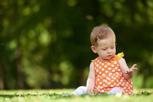 happy young baby child sittng on grass on beautiful summer day in park